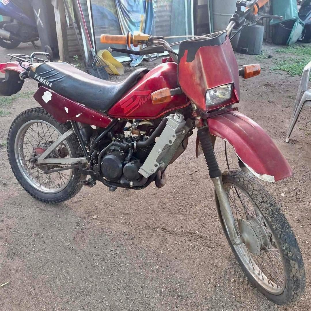 Moto Yamaha DT rouge avec un cache plastique manquant